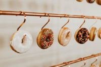 a stylish copper display with hooks and glazed donuts hanging is a very edgy idea for your wedding