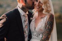 a stylish groom’s look with a black pantsuit, a white shirt and a floral print tie, groom’s tattoos on this hands and neck are shown in a great way