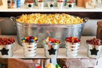 a super bright and fun popcorn bar with buckets and bathtubs, lots of colorful popcorn and candies and paper bags for serving