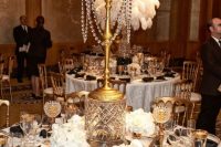a super glam and exquisite 1920s tablescape with a tall candleholder, white blooms, gold rimmed glasses and black napkins