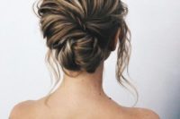 a textured messy twisted and braided low updo with locks down for a modern romantic bride
