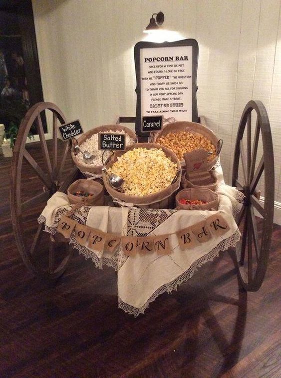 a vintage trolley popcorn bar with a lace blanket, a burlap banner, popcorn in wooden baskets and chalkboard signs