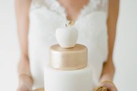 a white and gold wedding cake topped with a glazed apple and served with various nuts is a very catchy and whimsical idea