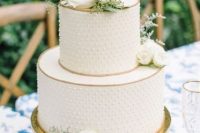 a white polka dot wedding cake with gold trims, white blooms and greenery is a stylish and chic idea for a neutral spring or summer wedding