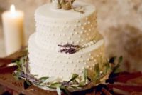 a white wedding cake with dimensional polka dots, with bird cake toppers and some lavender and greenery is amazing