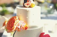 a white wedding cake with some dimensional polka dots, bright blooms, coupel cake toppers and a banner is a lovely solution for a summer wedding
