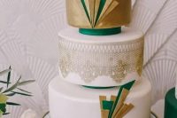 an art deco wedding cake with metallic gold decor and layers, gold lace and emerald touches