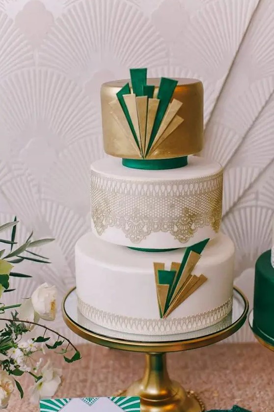 an art deco wedding cake with metallic gold decor and layers, gold lace and emerald touches
