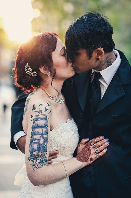 an elegant groom's outfit with a three piece black suit, a white shirt and a black tie doesn't prevent him from showing off his neck tattoos