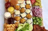 build your own burger bar board with burgers, vegetables, French fries, greenery, sauces and dips