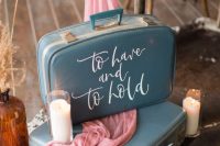 lovely and dreamy wedding decor with a couple of blue suitcases, pink fabric, pillar candles and calligraphy is amazing
