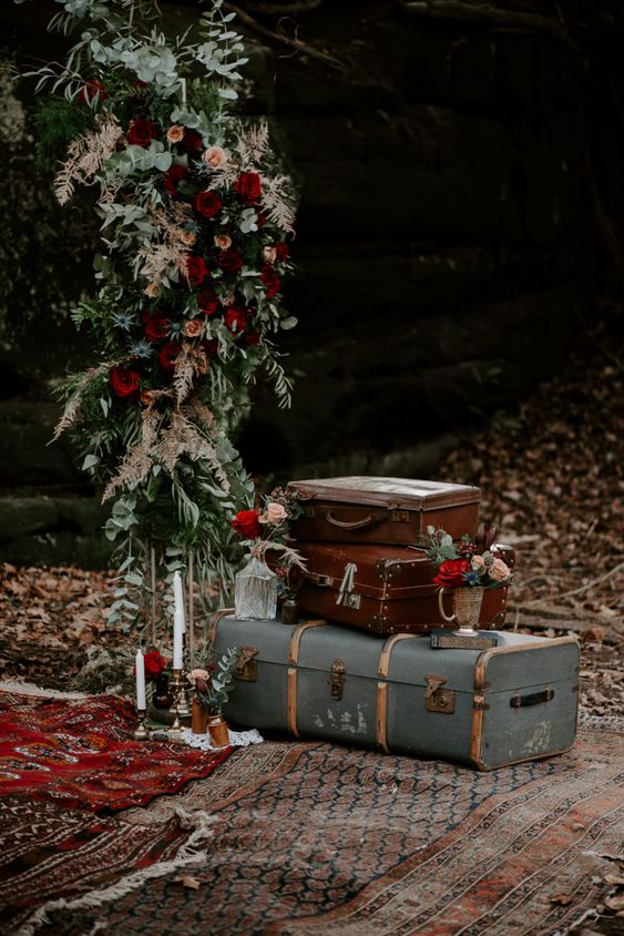 moody fall wedding decor with a stack of vintage suitcases, bold blooms and greenery is a simple and cool idea for a fall wedding