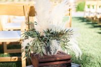 wedding ceremony space decor with a wooden crate, a vintage suitcase, an arrangement of greenery and pampas grass