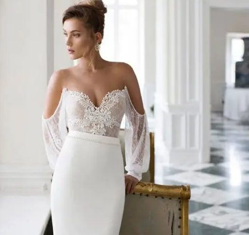 an incredibly sexy off the shoulder wedding dress with a lace bodice and puff sleeves and a plain skirt catches an eye with its deep neckline