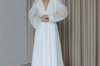21 an elegant A-line wedding dress with a pleated skirt with a train, a plunging neckline and illusion sleeves is wow