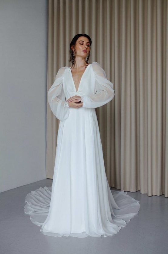 an elegant A-line wedding dress with a pleated skirt with a train, a plunging neckline and illusion sleeves is wow