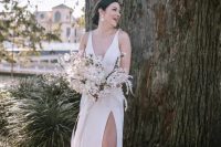 32 a modern glam bride wearing a plain A-line wedding dress with no sleeves, a deep neckline and a front slit, nude shoes and statement earrings