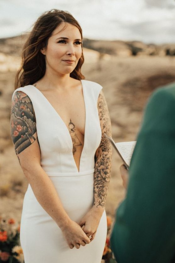 a modern plain sheath wedding dress with a plunging neckline, no sleeves showing off the tattoos for even a sexier look
