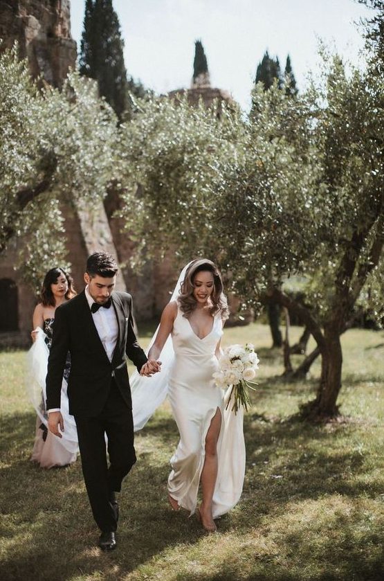 a modern refined wedding look with a silk slip wedidng dress with a deep neckline and a front slit plus a long veil is gorgeous