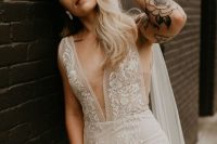 43 a sheath lace wedding dress with no sleeves and a plunging neckline plus tattoos that are shown off for a bold and sexy look