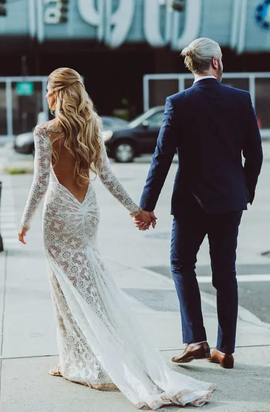 a boho lace mermaid wedding dress wiht a low back, long sleeves and a train for a sexy boho bridal look