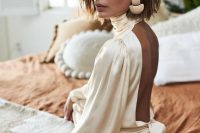 49 a champagne silk wedding dress with a turtleneck, an open back and a pleated skirt is a very eye-catchy and chic idea to try
