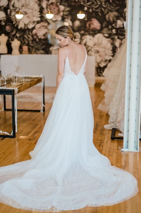 a chic A-line wedding dress with spaghetti straps, an open back and a long sweeping train looks beautiful