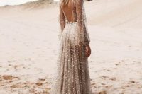 52 a fully embellished tan sheer wedding dress with a cutout back, long sleeves, a metallic belt and a train