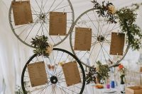 a bike wheel seating plan with greenery, neutral blooms and the plan itself is a stylish and cool idea for a wedding