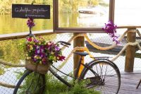 a black bike decorated with ferns and with a basket filled with super bright blooms and greenery is a gorgeous idea for a wedding