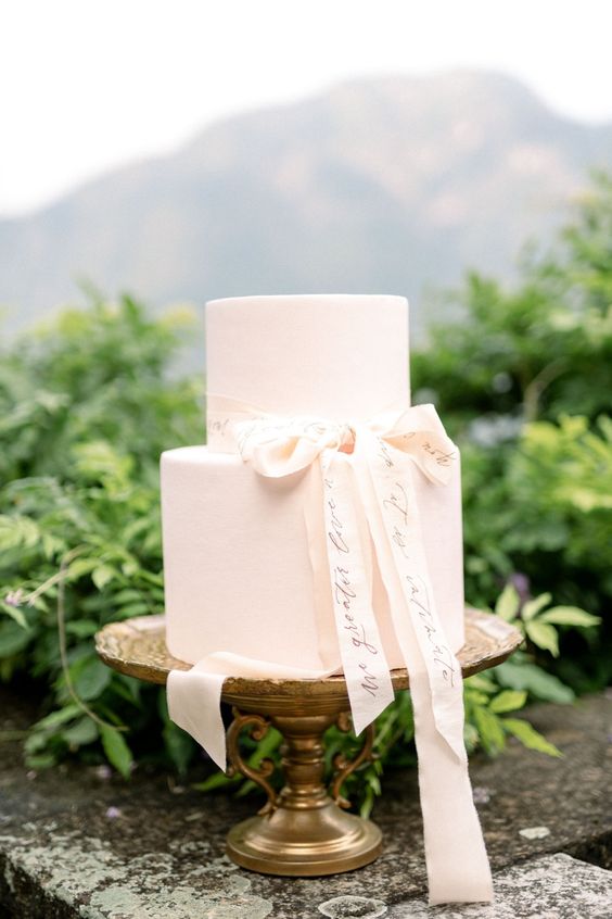 a blush wedding cake with a ribbon bow, and the ribbon with calligraphy is a dreamy and very romantic idea