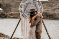 a boho wedding arch with a large dream catcher with fringe is a cool idea for any boho couple