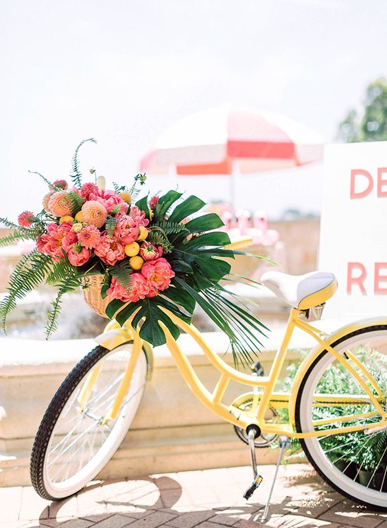a bold yellow bike with tropical leaves, bright pink and orange blooms and citrus is amazing for a tropical wedding