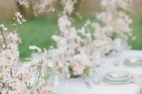 a breathtaking garden wedding tablescape done in pastel green and blush, with beautiful almond blossom centerpieces and green plates