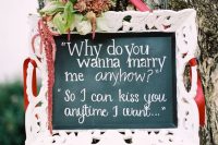 a chalkboard sign in a refined white frame, with burgundy blooms, greenery and ribbon is a lovely idea for a wedding in the fall