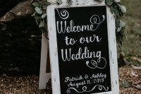 a chalkboard sign in a vintage white frame, with greenery, white and blush blooms is a lovely idea for a vintage rustic wedding