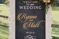a chalkboard sign with calligraphy, in a refined white frame and a gorgeous floral arrangement is a lovely idea for a wedding