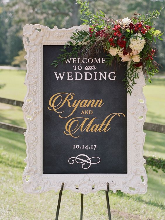 a chalkboard sign with calligraphy, in a refined white frame and a gorgeous floral arrangement is a lovely idea for a wedding