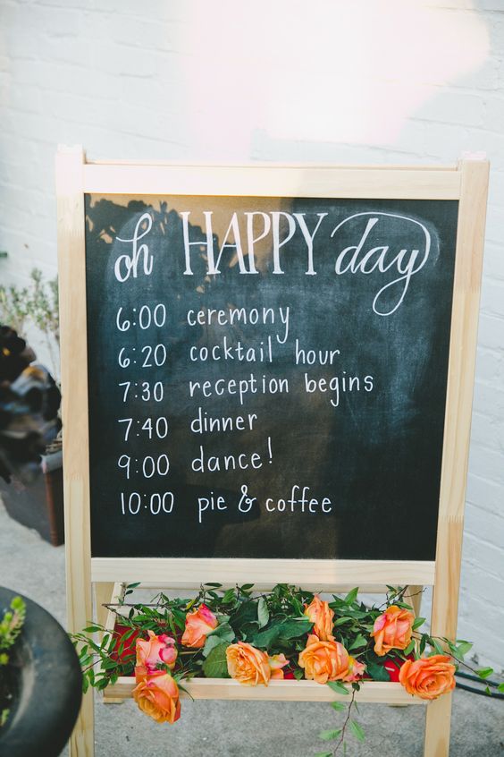 a chalkboard sign with the program of the day, on a stand with super bright blooms and greenery is amazing for a rustic space