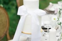 a chic and beautiful white wedding cake decorated with a single white ribbon bow is a gorgeous and tasteful solution for your wedding