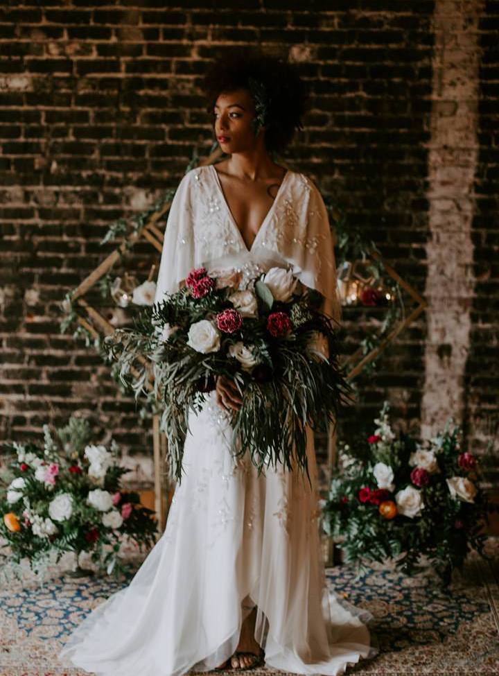 a chic art deco wedding gown with a plunging neckline, cape, train and floral embellishments