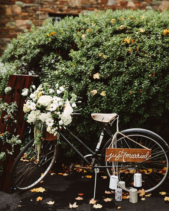 a chic bike decorated with greenery and white blooms, a plaque sign and tin cans will be a fun escape at your wedding