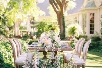a chic garden wedding table setting with neutral and pastel blooms, with greenery on the ground and on the table