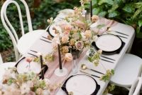 a chic secret garden wedding table setting with a pink runner, black candles, napkins and blush blooms and greenery