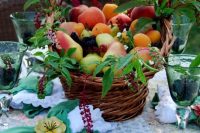 a creative wedding centerpiece of a basket with pears, apples, fresh berries, blooms and greenery for a garden wedding