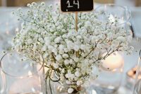 a delicate cluster wedding centerpiece of baby’s breath, floating and pillar candles and a chalkboard table number is a lovely idea for a wedding
