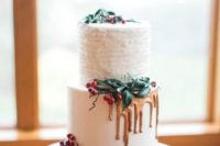 a frosted wedding cake with a ruffled layer, gold drip and mistletoe for a winter or Christmas wedding
