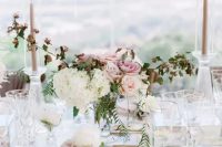 a glass table with candles and decor is very neutral and the centerpiece is of chic pink, blush and white flowers
