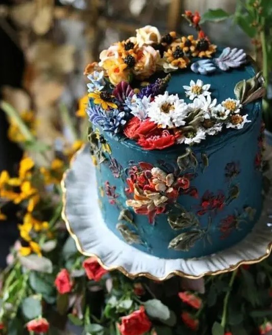 a jaw-dropping garden wedding cake in blue, with lots of sugar blooms and leaves of various colors is amazing