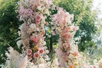 a jaw-dropping wedding arch with pink, orange and white blooms, dyed baby’s breath and pampas grass is gorgeous for a garden wedding